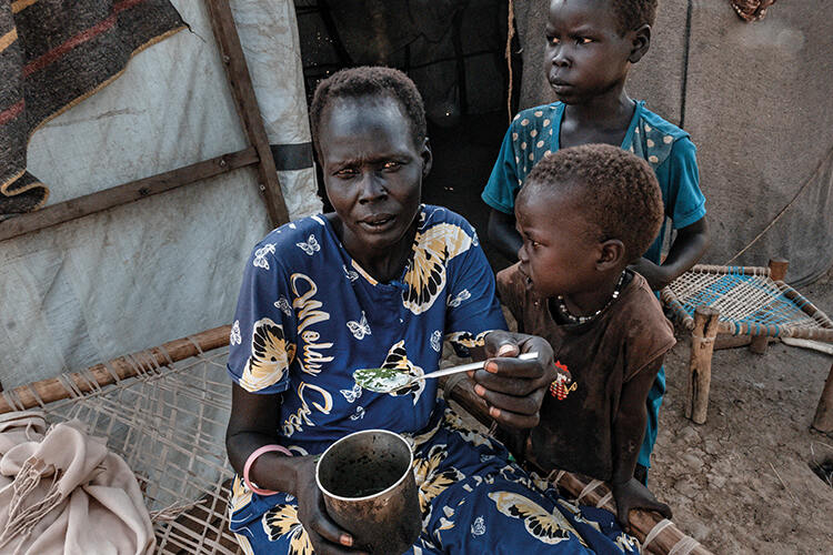 Achuei , a mother at Gongoi camp in South Sudan, shows the soup she made from wild leaves. ‘Sometimes we can find food, sometimes not. We are often hungry. Life is very hard for us: our shelter leaks, our mosquito nets are torn. We need help’