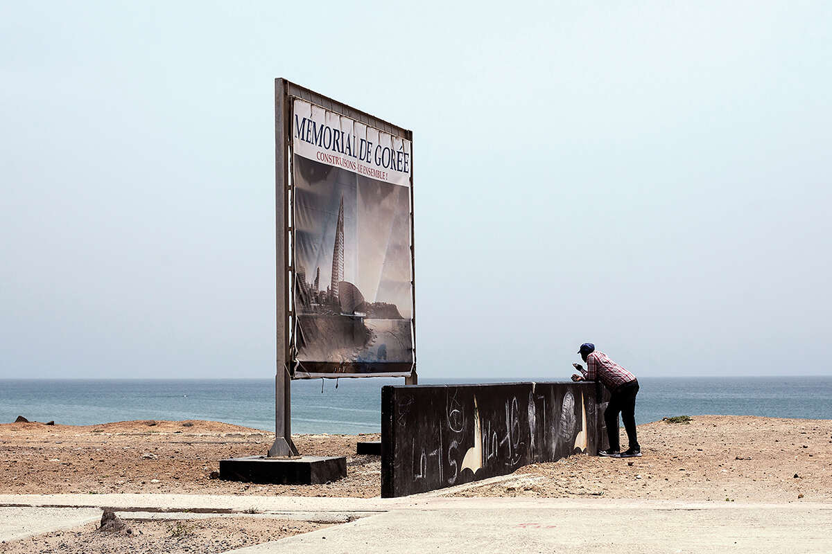 Man standing looking at a memorial on the Dakar Waterfront, Senegal 