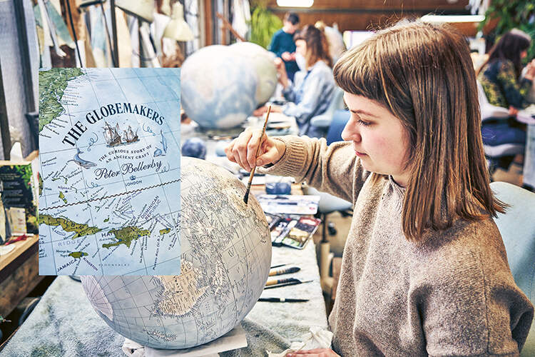 A little girl paints a globe in a workshop
