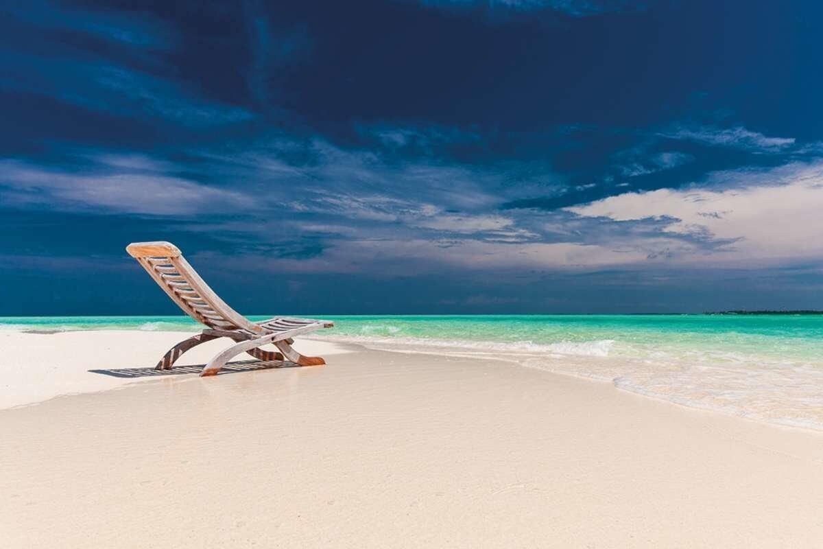 Tourism: sunlounger on a white sand beach