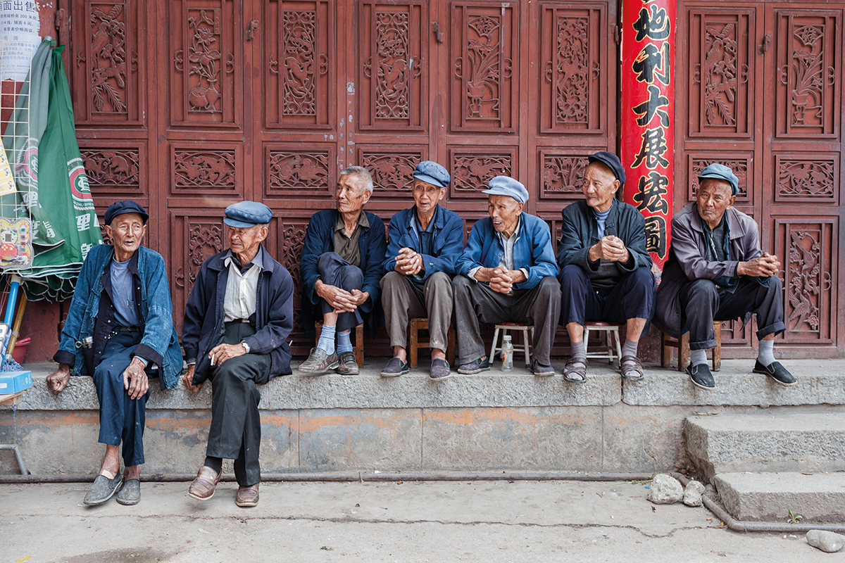 A line of elderly people sit in front of a social welfare home in Dali, China
