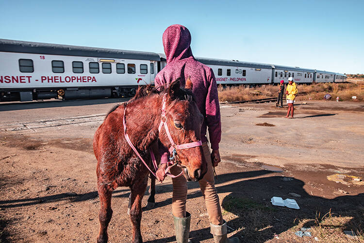 A boy looks on with his horse as the Phelophepa healthcare train arrives in Thaba Nchu in South Africa’s Free State province