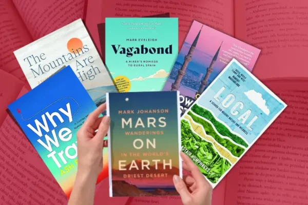 Selection of book covers held by a pair of hands from our hand-picked 'Best Travel Books 2024' list