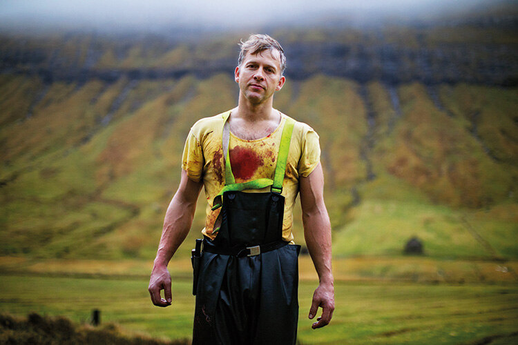 Hjalmar, his shirt stained with blood from the sheep he has been slaughtering on a farm in the village of Kaldbaksbotnur on the east coast of the island of Streymoy