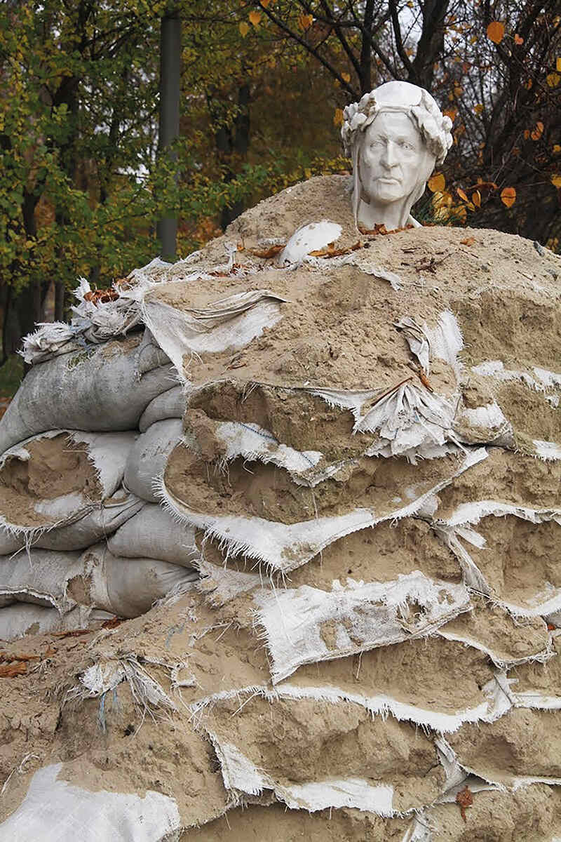 A sandbagged statue of dante in a park in Kyiv