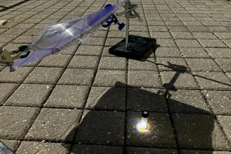 Inside this reaction vial, spotlit by concentrated sunlight, a piece of black polystyrene from a foam tray breaks down into a recyclable material.