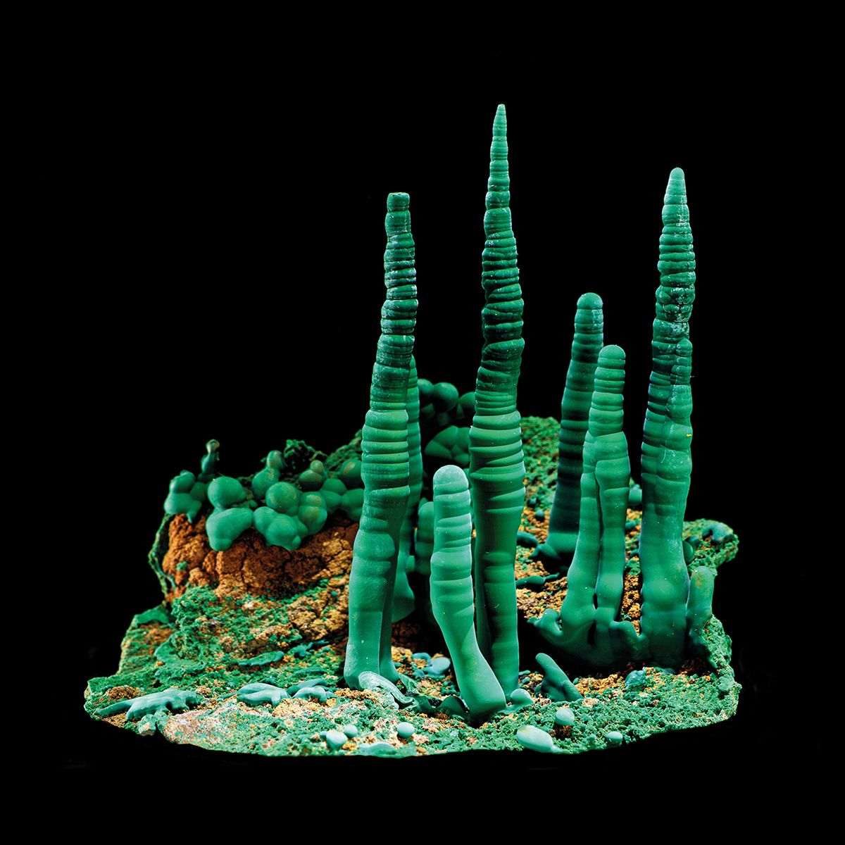 Towers of green and orange malachite against black background