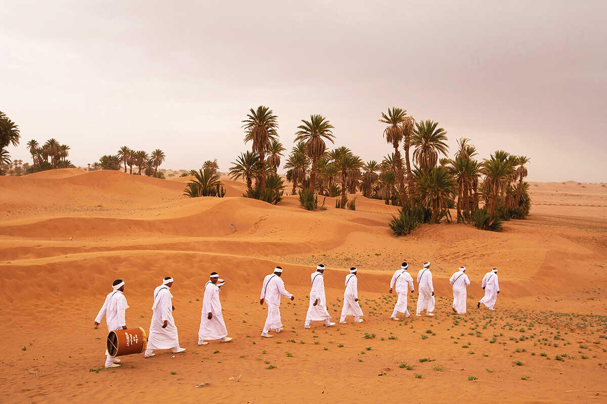 Musicians walk through a desert performing a traditional rain chant 