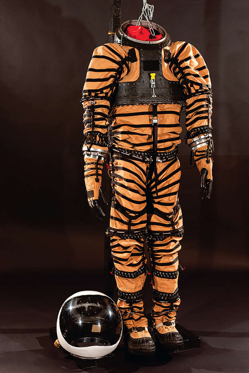 Orange and black North Dakota eXperimental-1 spacesuit hanging up in museum