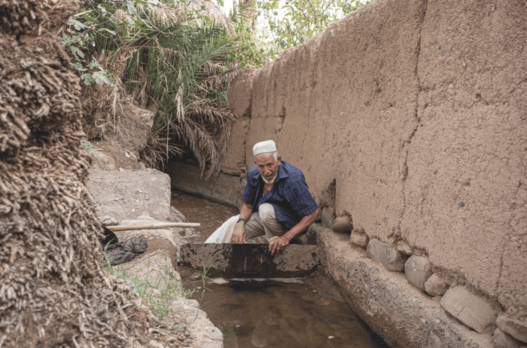 Ahmed El Mandori, 72, opens the canal that allows him to receive water from the Khettara irrigation system, twice a week, to irrigate date palm fields.