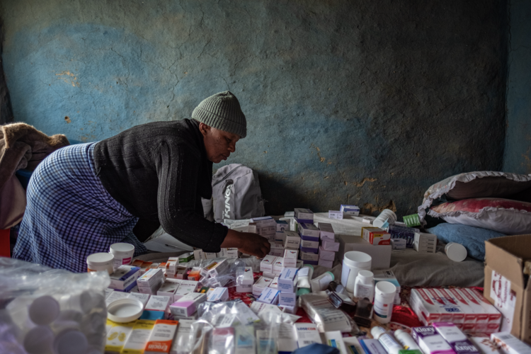 An outreach health worker searches through diminishing medical supplies in an isolated village