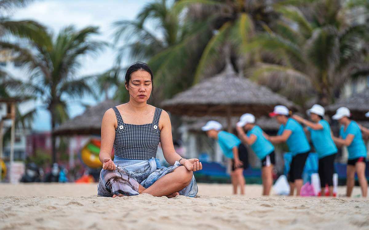 A woman meditating on a beach in Danang, Vietnam