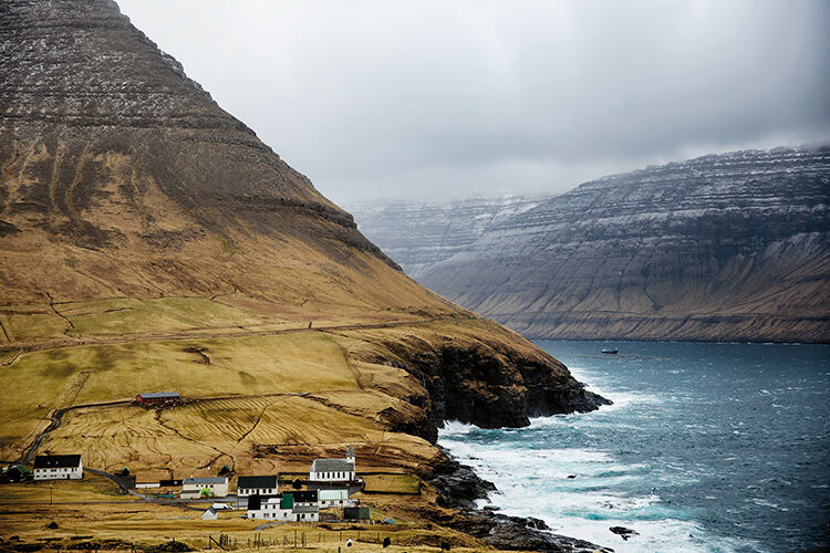The small town of Vidareidi on the island of Vidoy, the northernmost settlement in the Faroe Islands. The houses are spread out across an evergreen valley, protected by high mountains on two sides