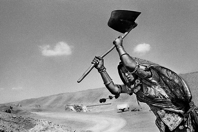 Woman do the hard manual work digging a canal in Rajasthan, India, while the men work as stone masons, 1990