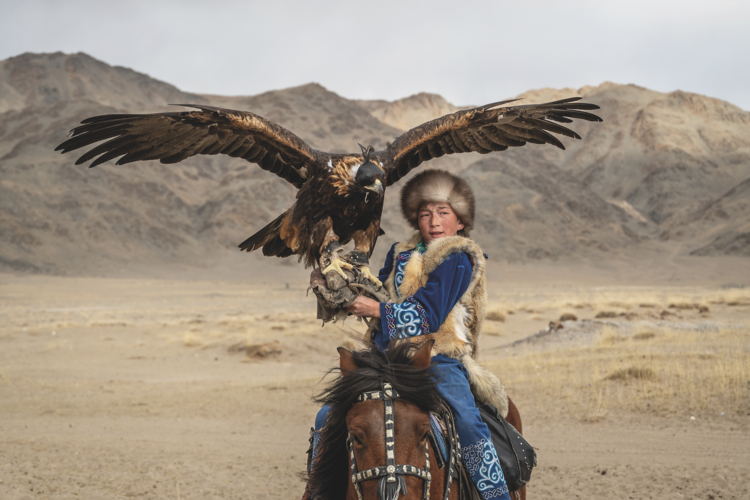 In the isolated wilds of the Altai Mountains, 12-year-old Aykerim holds a golden eagle outside her family’s home