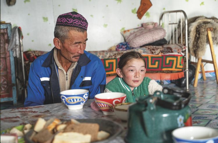 Aykerim, 12, sits with her
father, Rakhimbyek