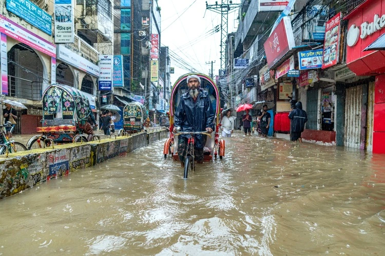 Chittagong, Bangladesh - August 22, 2024 : Rickshaw puller trying to drive through a Flooded street in Chittagong, Bangladesh. Water logging in Chawkbazar, Chittagong City.