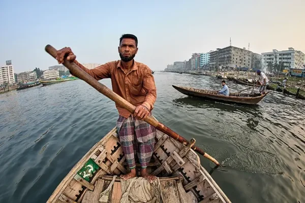 A man paddles his water taxi down the Buriganga River, which flows through the heart of Dhaka