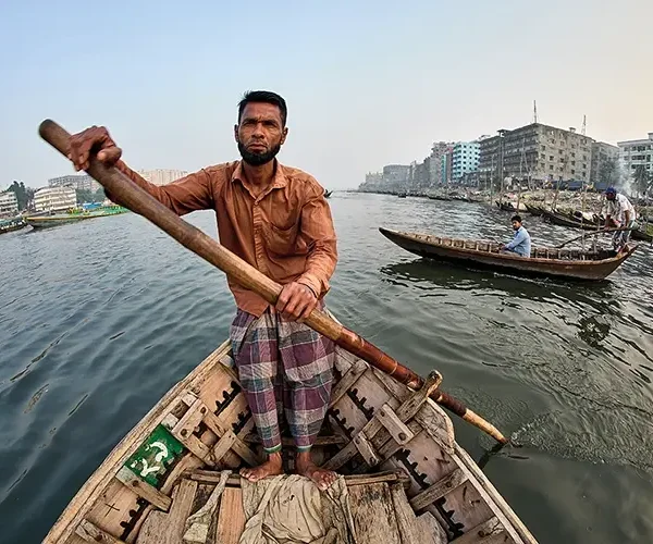 A man paddles his water taxi down the Buriganga River, which flows through the heart of Dhaka
