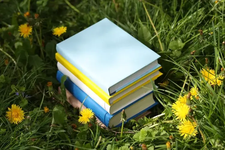 Books in grass surrounded by some flowers