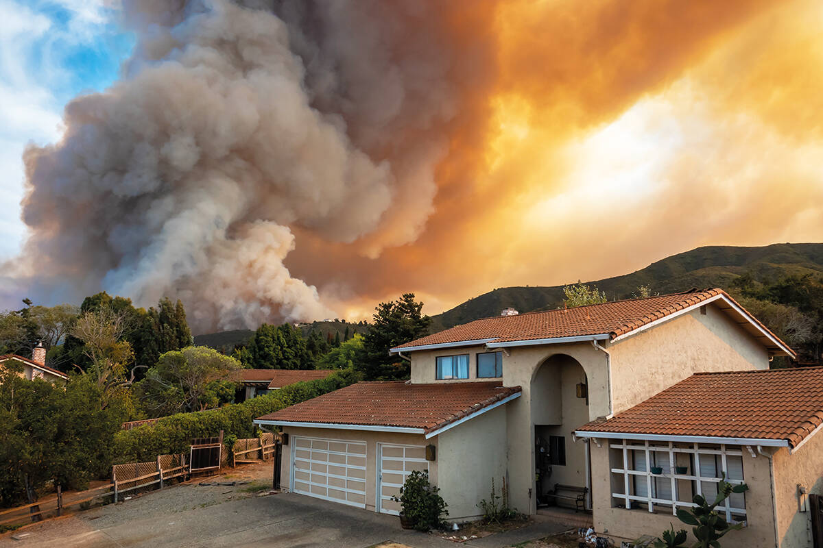 A wildfire burns behind houses in the hills of California