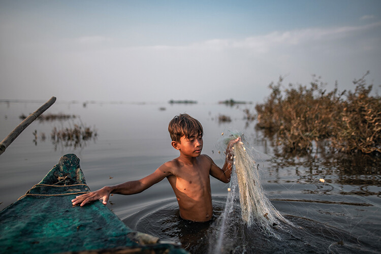Pheak Pheap, 12, brings in his meagre catch in the evening outside the floating village of Oakol