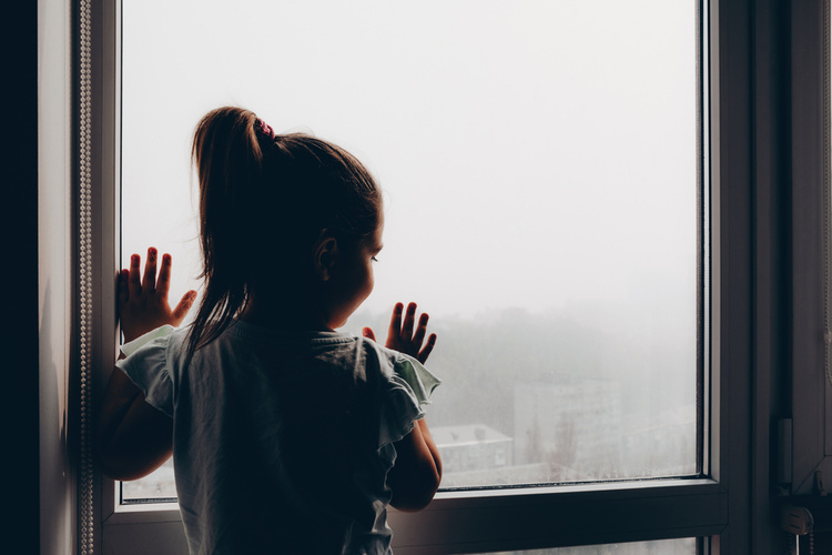 Child looks out the window at smog