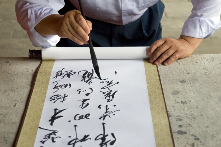 A Chinese calligrapher at work writing on a scroll