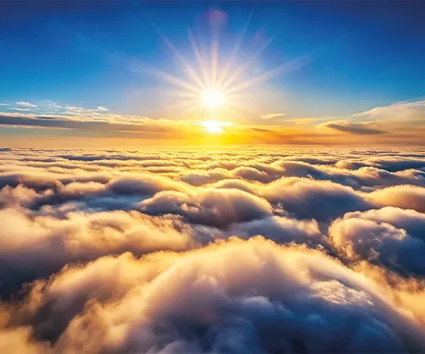 Glowing clouds below sun during sunrise