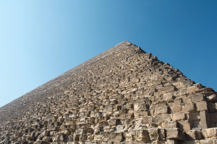 Close-up photo of the Great pyramid, view pointing upwards showing the top of the pyramid, the rocks that it is composed of.