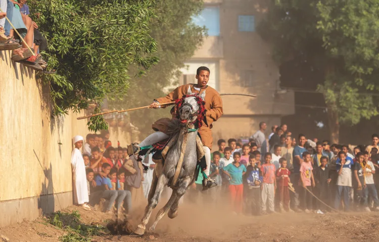 A rider charges past a crowd of children at the Mermah