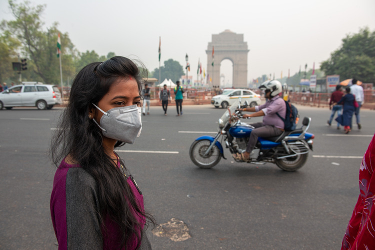 New Delhi, India-September 30 2019: woman in mask visiting india gate during air pollution, famous landmark and the local citizens come to relax with their families and friends.