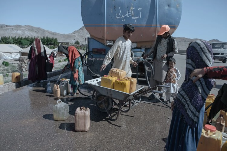 The drought-displaced Afghan children fill water containers to carry to their tents from a tanker at a camp for internally displaced people on the outskirts of Herat province. 