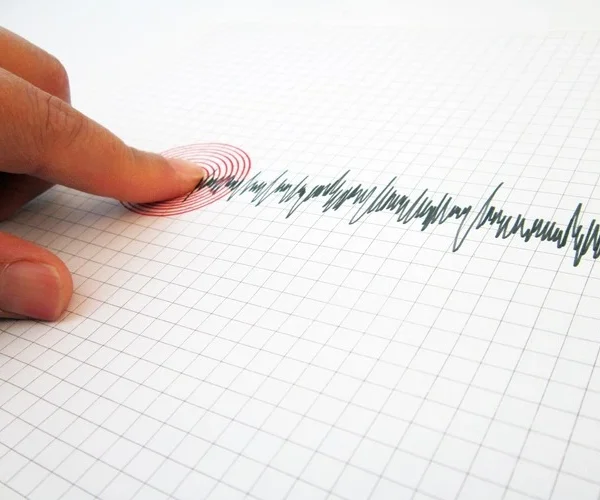 Seismograph and earthquake. A hand pointing at a seismograph recording the seismic activity of an earthquake