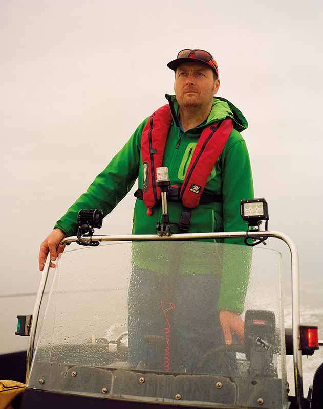 A man steering a boat at an oyster reef restoration site