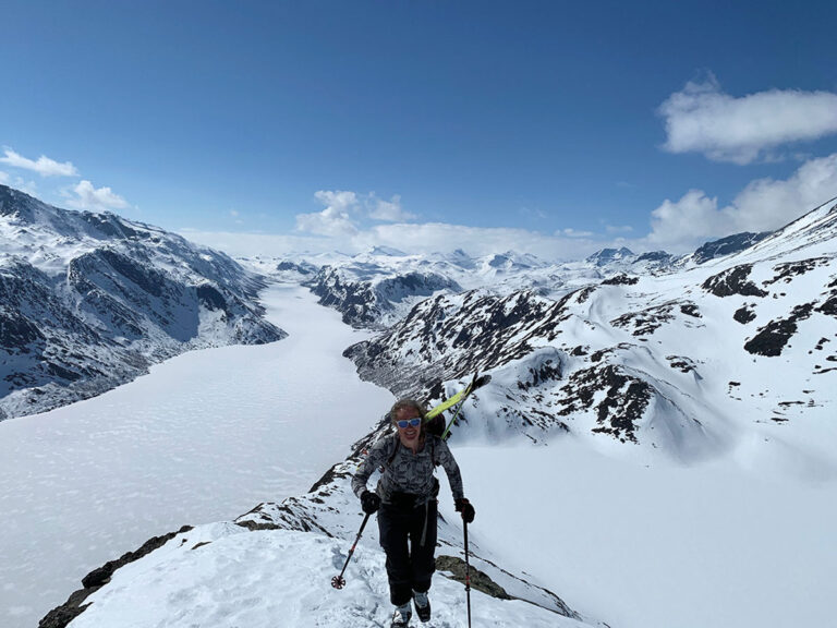 A woman crosses a snowy besseggen ridge in Norway