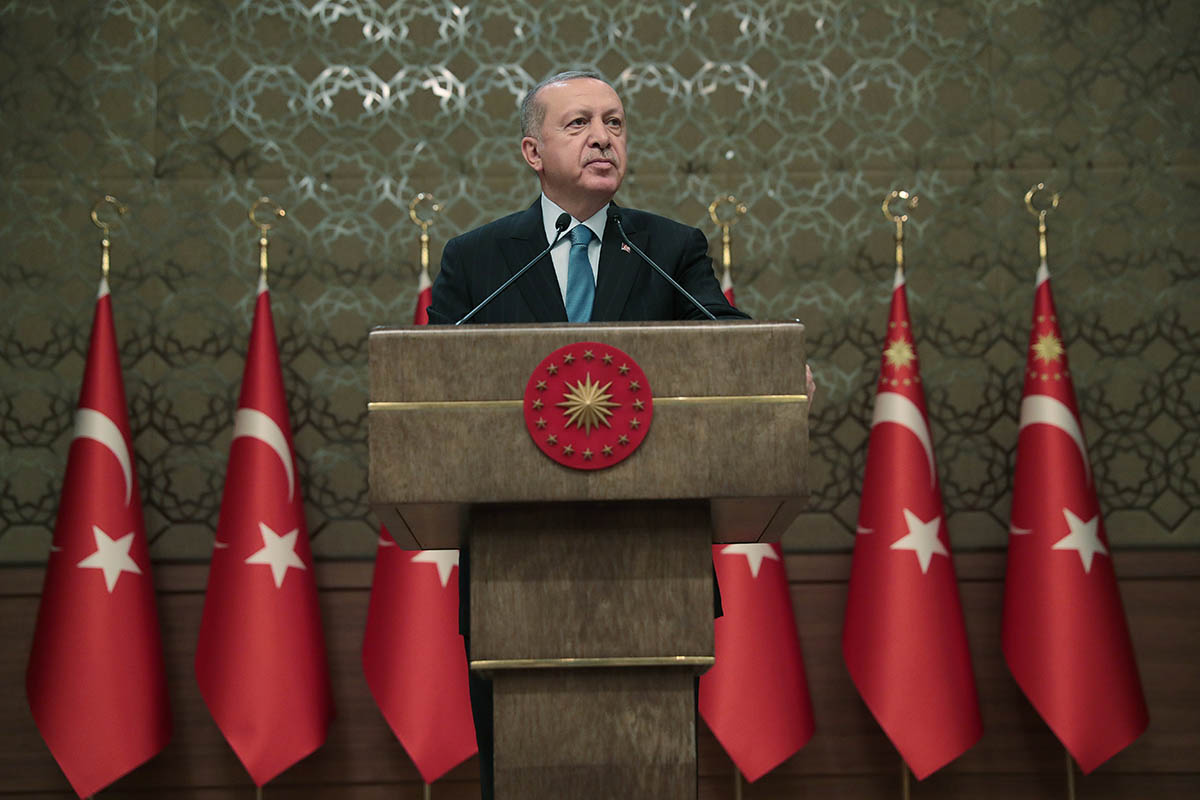 Turkey president Recep Tayyip Erdogan standing at a podium infront of turkish flags doing a speech