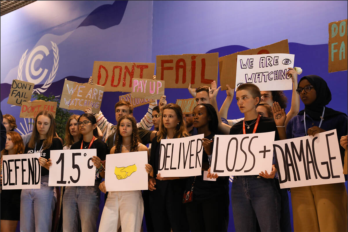 a group of young people stand on stage at the conference holding protest signs