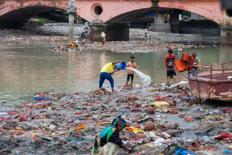 Muradnagar, Uttar Pradesh; India-Oct 18 2021: People putting waste into the Ganges River