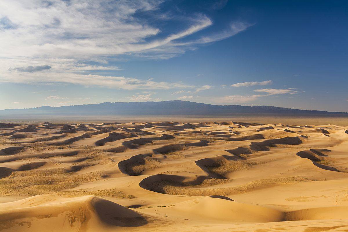 The flat Gobi Desert with blue sky and mountains in the background