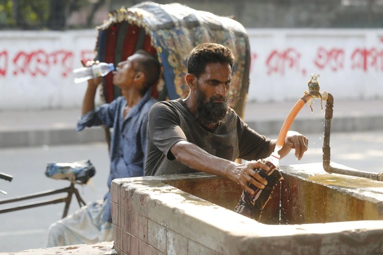 DHAKA, BANGLADESH- APRIL 30, 2024: A man is collecting drinking water from a roadside during a heatwave in Dhaka, Bangladesh on April 30, 2024.