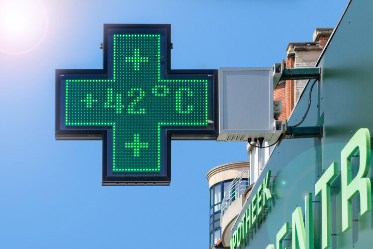 Thermometer in green pharmacy screen sign displays extremely hot temperature of 42 degrees Celsius during heatwave in summer in Belgium