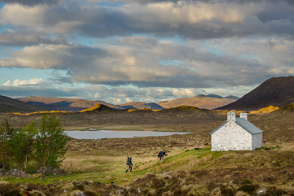 Two hikers approach a mountain shelter on the Cape Wrath Trail in the Scottish Highlands 