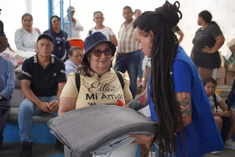 An IOM staff member hands over essential relief items to a woman affected by the earthquake in Quindío during a humanitarian assistance distribution.