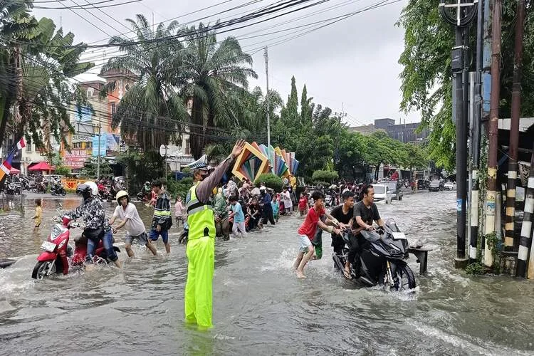 Jakarta, Indonesia - February 14, 2024 : traffic safety officers controlling traffic because there is flooding in the area of Indonesia.