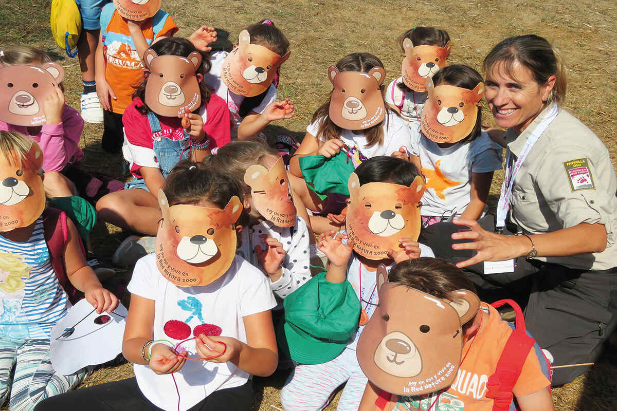 A group of children looking at the camera wearing cantabrian brown bear masks