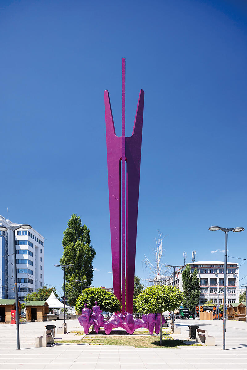 A purple statue sits against blue sky in Kosovo