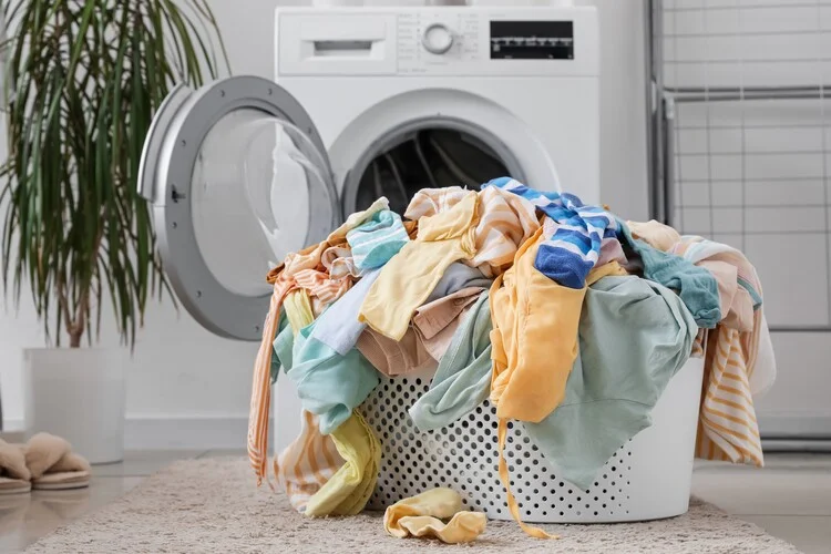 Basket with dirty clothes on floor in laundry room