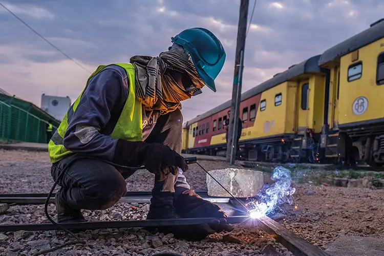 Workers repair a damaged fence protecting a diesel depot at Huambo train station, Angola