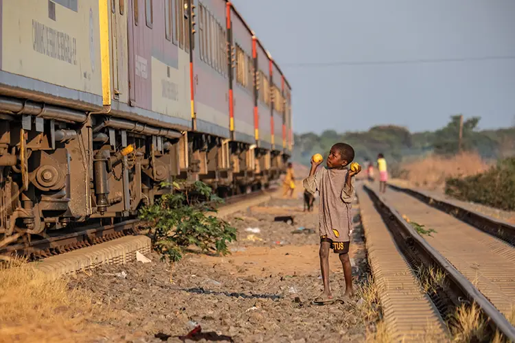 A boy sells mangoes to Lobito Atlantic Railway passengers in Angola’s central highlands